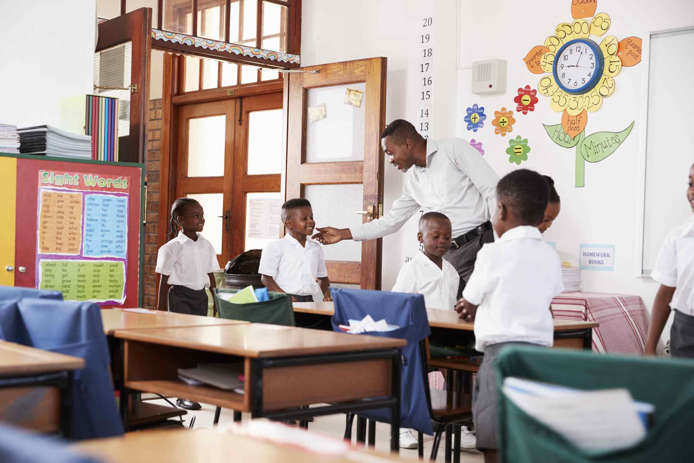 Teacher greeting children arriving at school