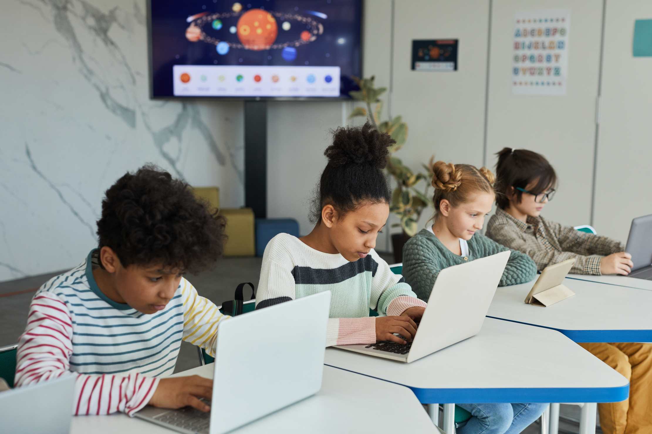 Students sitting in a row using computers in class